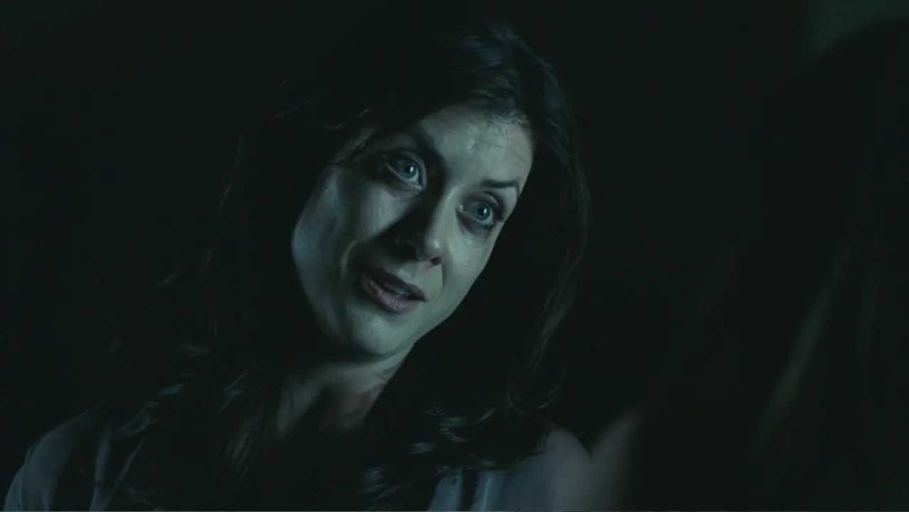 Legion (2010) movie still: closeup — A dimly lit room provides a dark background for the close-up shot. A woman with tear-stained cheeks looks at…