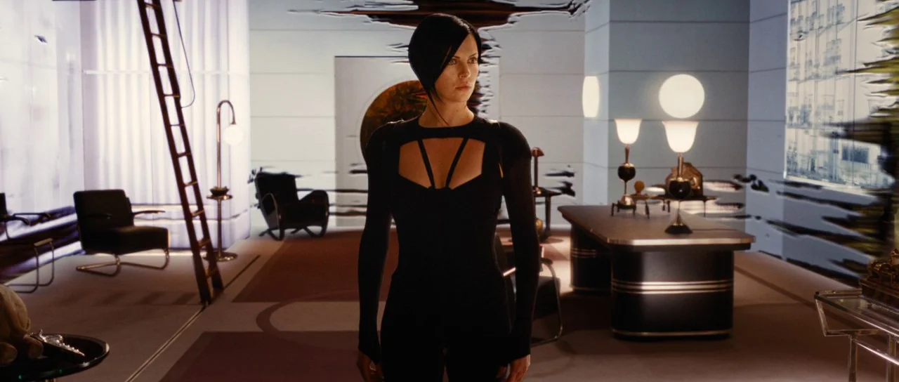Aeon Flux (2005) movie still: fullbody — A minimalist, modern room features dark furniture and a wooden ladder leaning against walls. A woman in a…