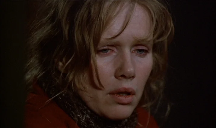 The Serpent’s Egg (1977) movie still: closeup — A dark, dimly lit room provides a minimalist backdrop for the character portrait. A woman with…