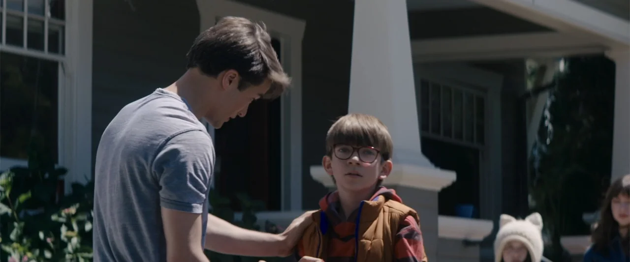 A Christmas Mystery (2022) movie still: medium — A residential front porch features painted trim and a visible house facade behind subjects. An…