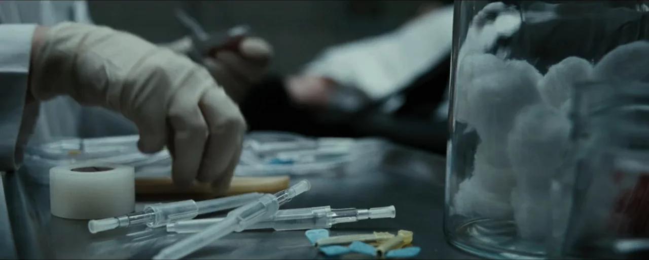 Law Abiding Citizen (2009) movie still: closeup — A clinical metal table holds various medical instruments including syringes, adhesive tape, and…