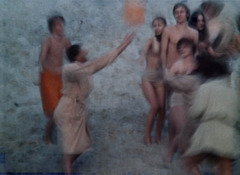 Fruit of Paradise (1970) movie still: fullbody — A group of young people gather on a sandy beach. They play with a small orange ball while wearing…