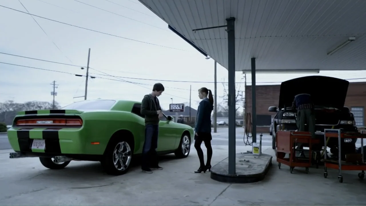 Ben 10: Race Against Time (2008) movie still: wide — An open gas station pump island with a bright green muscle car parked alongside. A teenage boy…