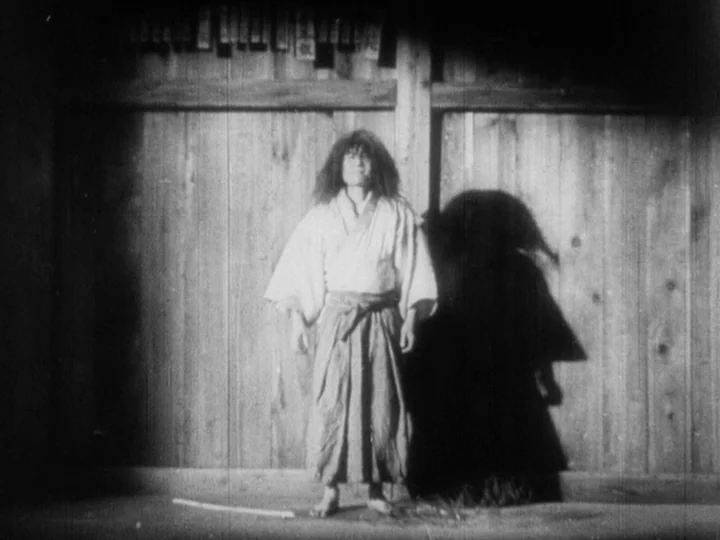Sanshiro Sugata Part II (1945) movie still: fullbody — A person stands against a wall of vertical wooden planks with paper slips attached. The…