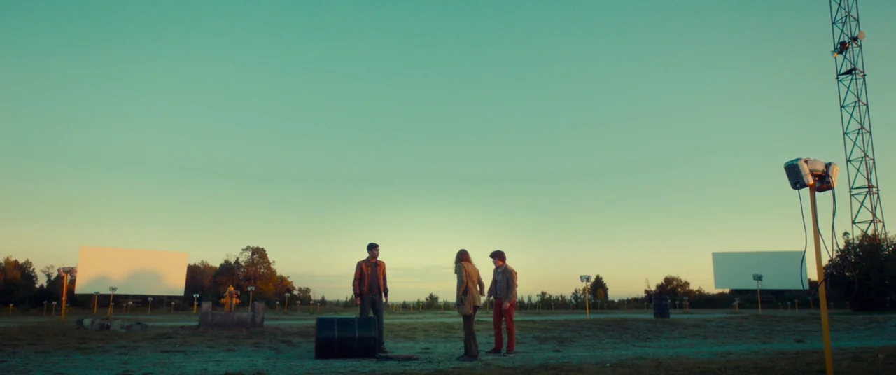 Scary Stories to Tell in the Dark (2019) movie still: wide — A vast, empty gravel lot contains two large white projection screens and metal towers.…