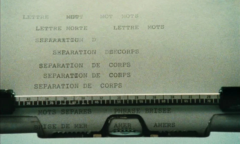 Documenteur (1981) movie still: closeup — A close-up of a typewriter page with repeating French phrases typed on white paper. The metal typewriter…