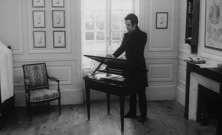The Wild Child (1970) movie still: fullbody — A study with pale wood floors features paneled walls and multiple framed botanical prints. A man…