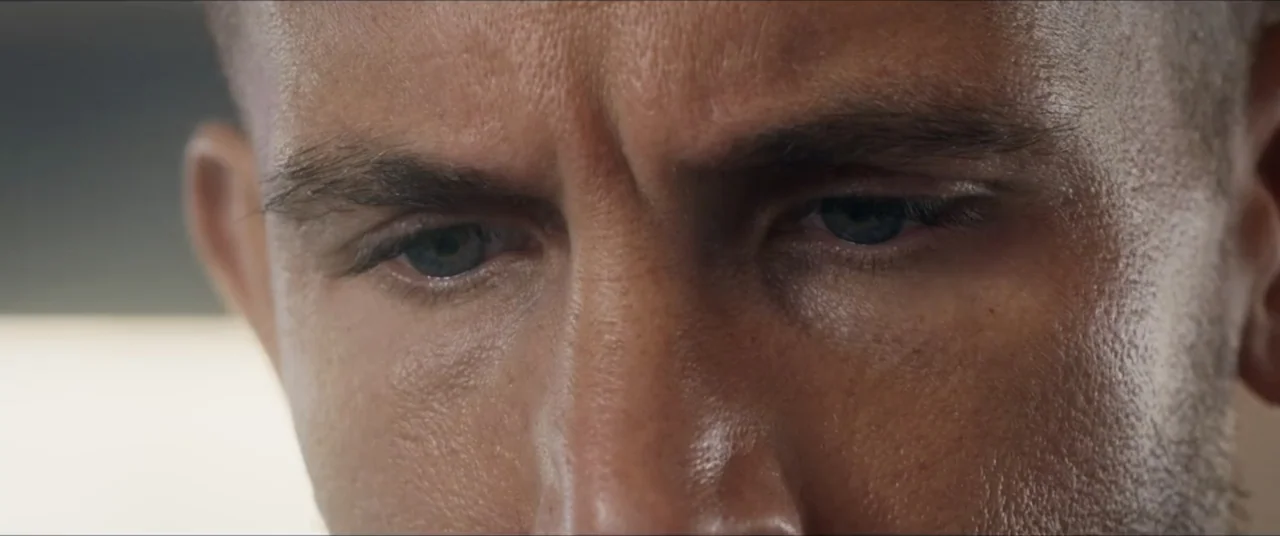 Man with No Past (2025) movie still: closeup — A close view shows the upper face and eyes of a man. The subject looks down with skin texture and…
