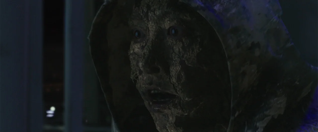 Along with the Gods: The Two Worlds (2017) movie still: closeup — A dimly lit, shadowed space containing a person with a heavily textured, darkened…