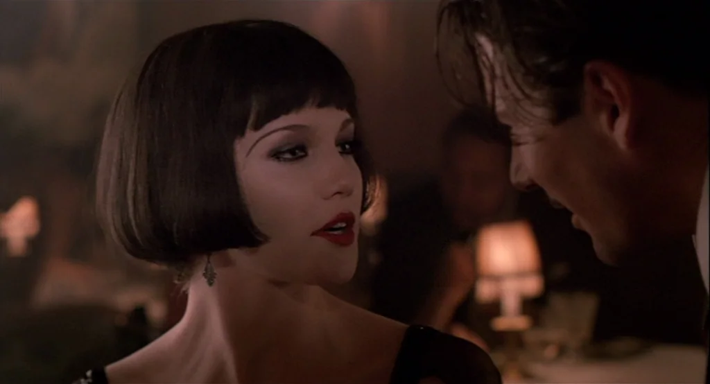 The Cotton Club (1984) movie still: closeup — A dimly lit club environment with warm lamp glows visible in the out-of-focus background. A woman in a…