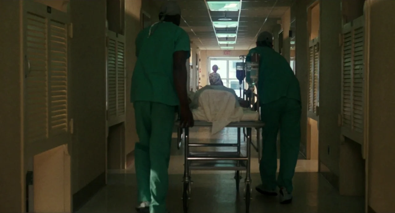 The Rain People (1969) movie still: fullbody — A long, dimly lit hospital hallway features rows of closed wooden louvered doors. Two medical staff…