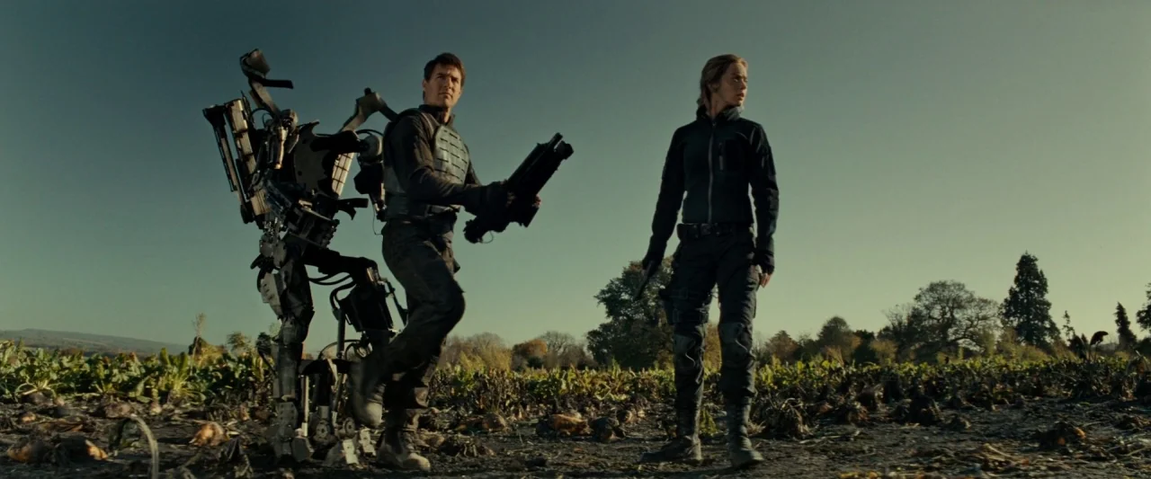 Edge of Tomorrow (2014) movie still: fullbody — A desolate agricultural field under a clear sky shows rows of harvested crops. Two soldiers in…