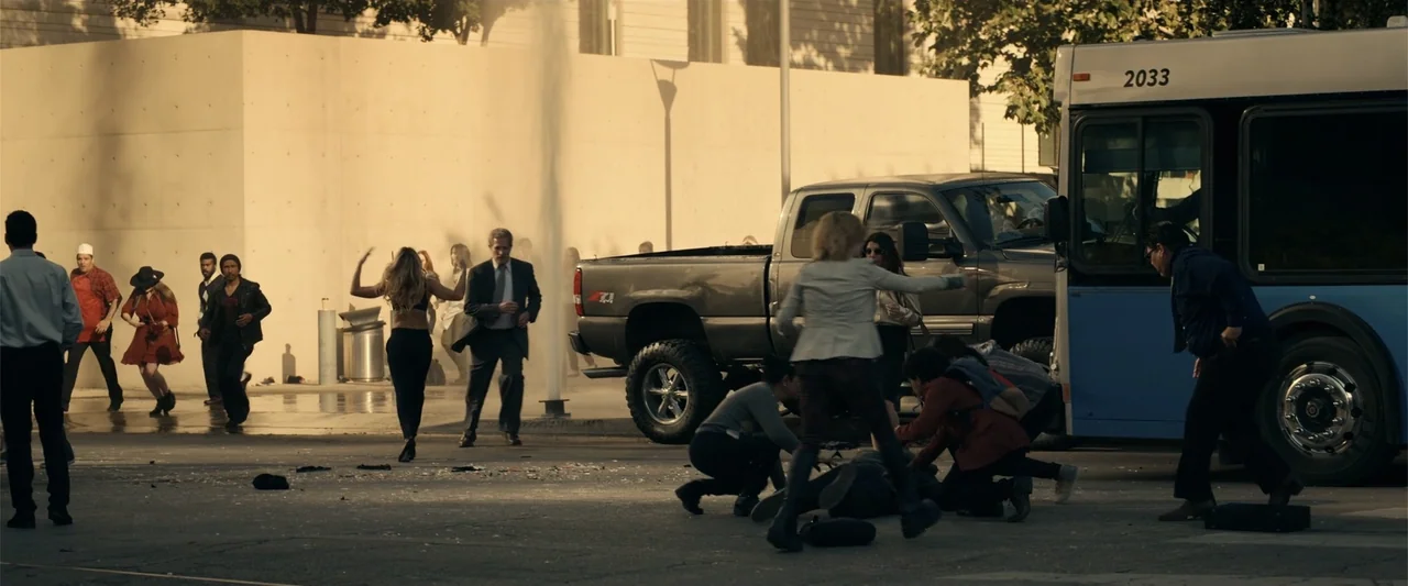 Hypnotic (2023) movie still: wide — An urban intersection features a concrete wall, a grey pickup truck, and a bus. Several people in modern attire…
