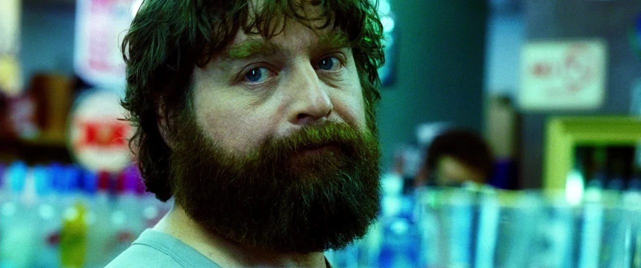 The Hangover Part III (2013) movie still: closeup — A man with a thick beard stands in an aisle at a convenience store. He looks directly at the…