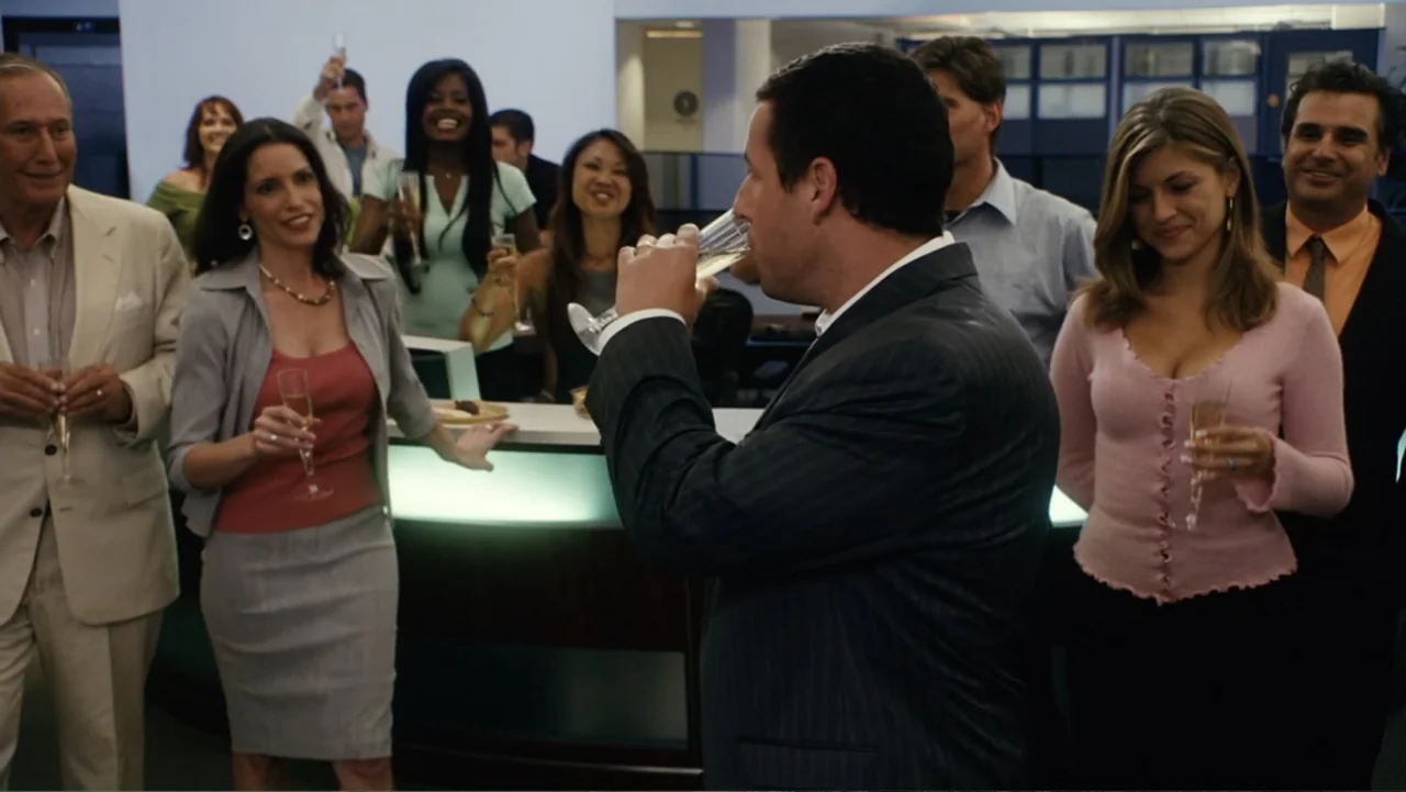 Click (2006) movie still: medium — A group of colleagues stands in an office breakroom area near a serving counter. A man stands in the foreground…