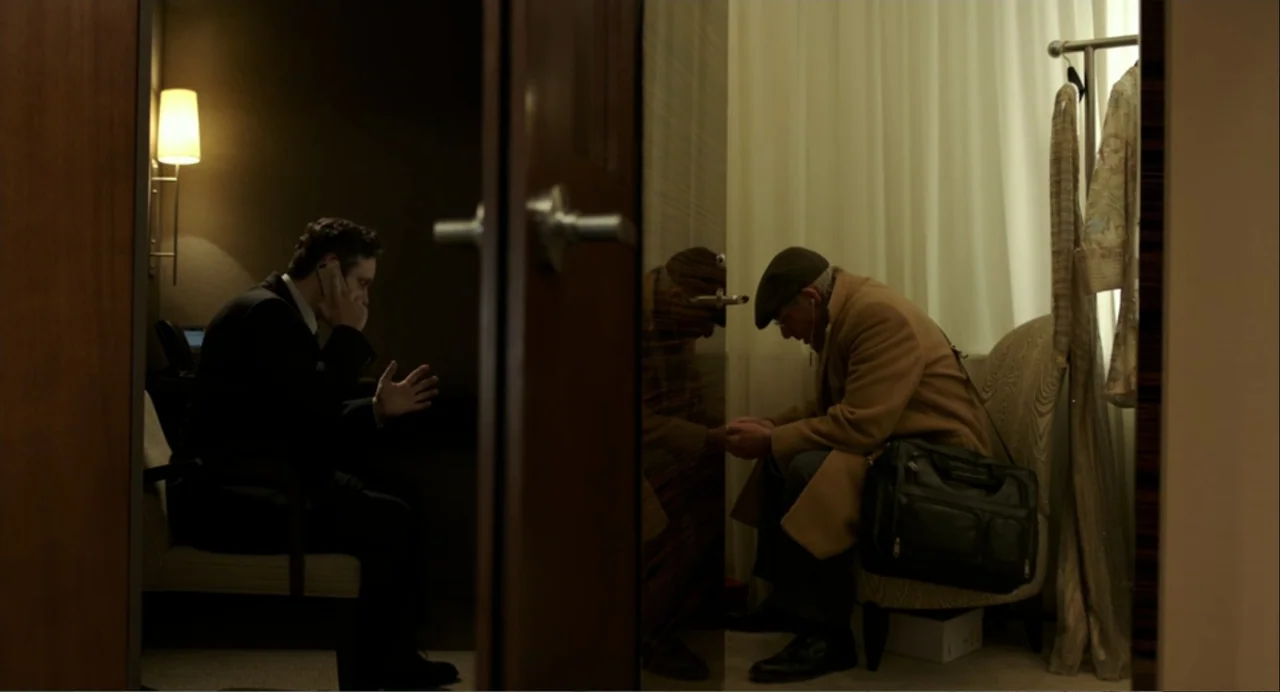 Norman: The Moderate Rise and Tragic Fall of a New York Fixer (2016) movie still: medium — A split composition shows two men in separate areas of a…