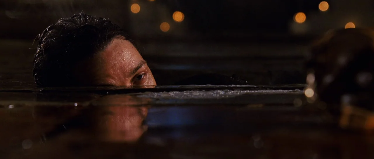 Wanted (2008) movie still: closeup — A man's face and eyes are partially submerged in dark water. Reflections of distant soft lights glimmer on the…