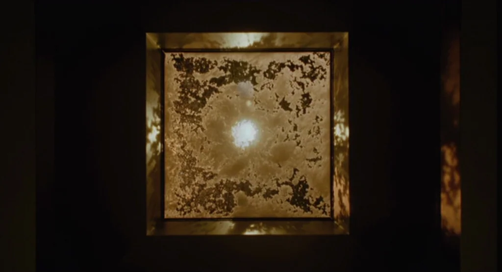 The Fountain (2006) movie still: closeup — A dark square chamber features a bright, textured skylight centered in the frame. The illuminated pane…