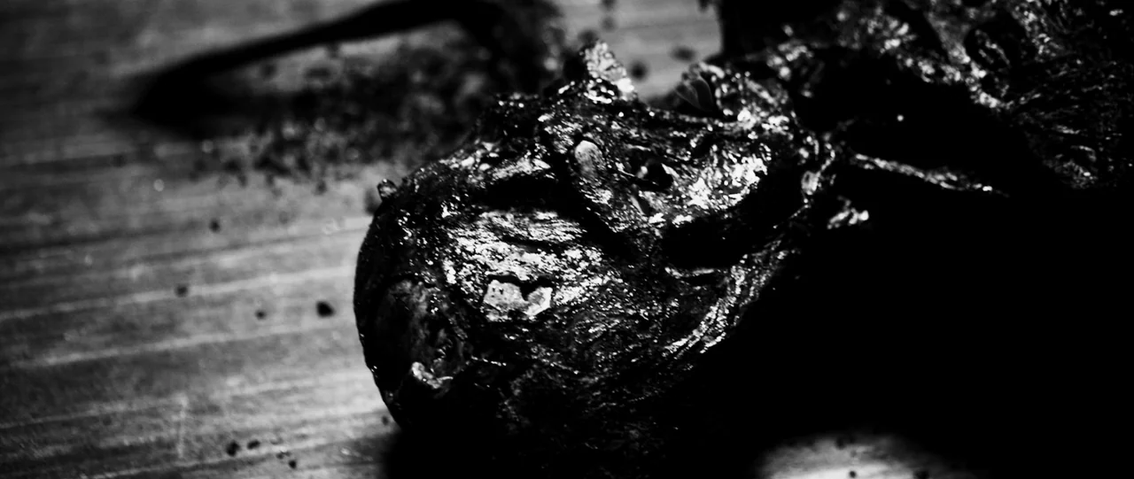 The Haunting in Connecticut (2009) movie still: closeup — A close-up shot of a dark, charred organic object on a wooden surface. The surface is…