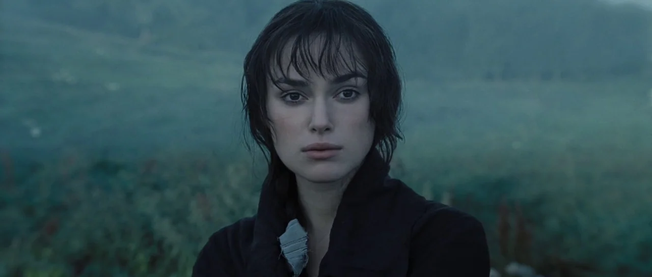 Pride & Prejudice (2005) movie still: closeup — A field covered in vegetation during the early morning hours with soft blue light. A woman with dark…