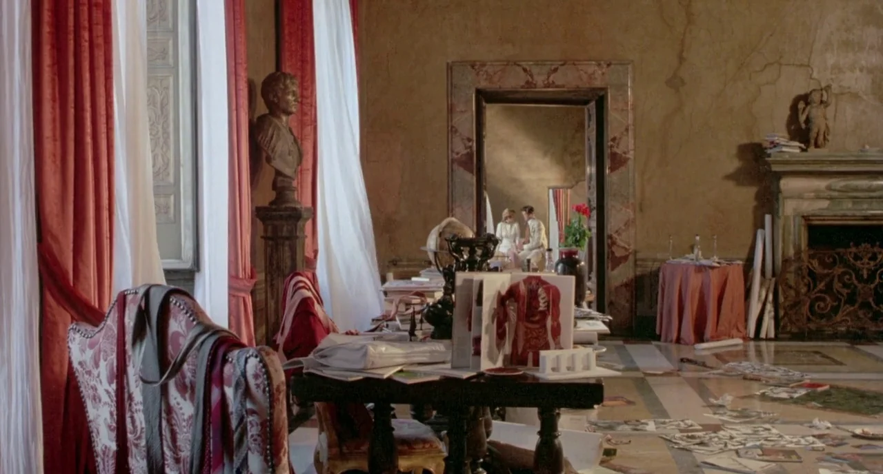 The Belly of an Architect (1987) movie still: wide — A spacious, weathered study features classical architectural details, red curtains, and a stone…