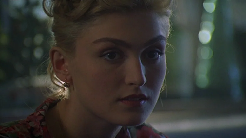 One Hundred and One Nights (1995) movie still: closeup — A dimly lit indoor space with blurred background foliage visible through a window. A young…