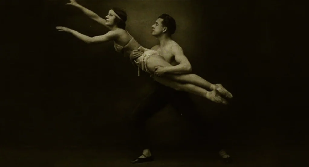 Sidewalls (2011) movie still: fullbody — A dark, empty photo studio provides a plain background for two dancers. A man lifts a woman horizontally,…