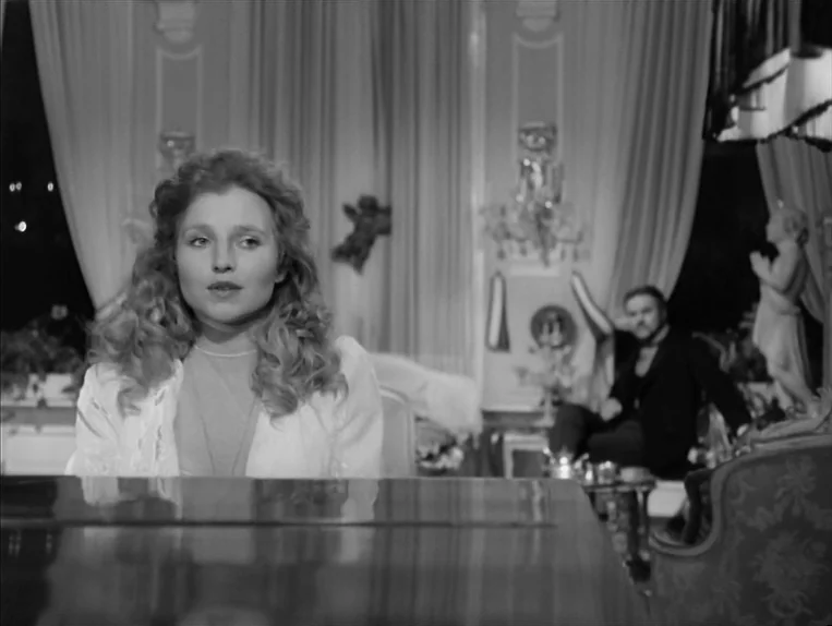 Effi Briest (1974) movie still: medium — An opulent, classic room with floor-to-ceiling sheer curtains and ornate wall molding. A young woman sits…