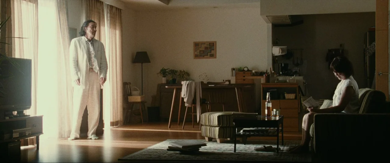 The World of Kanako (2014) movie still: wide — A spacious apartment interior features mid-century modern furniture and wide windows with sheer…