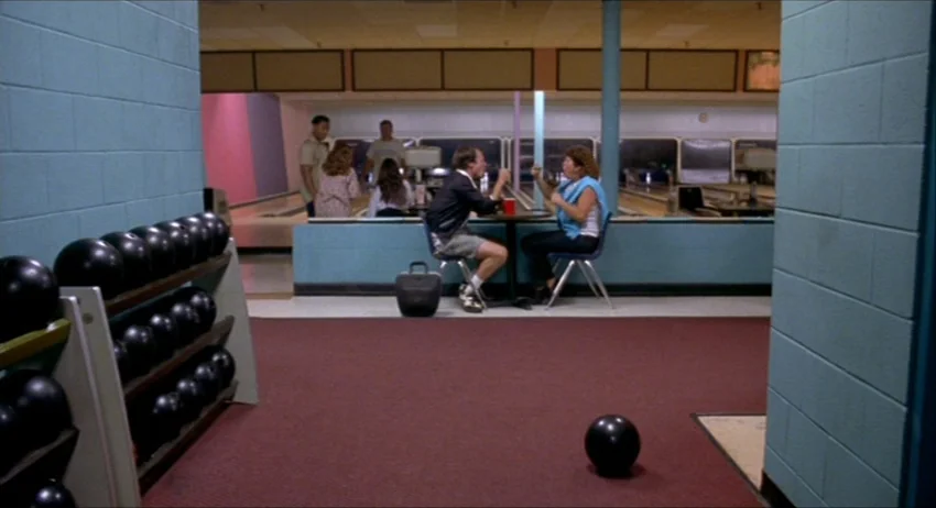 Gummo (1997) movie still: wide — A quiet indoor bowling alley with light blue cinder block walls and red carpeting. A man and a woman sit facing…