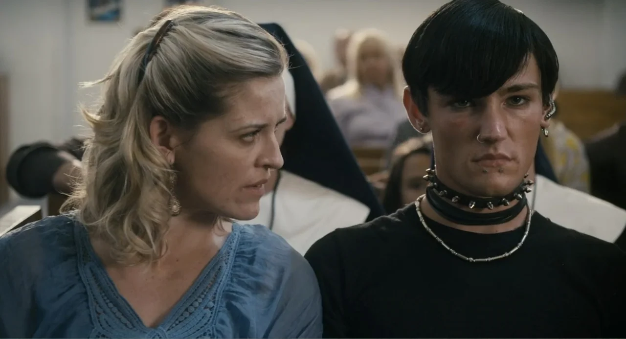 Gates of Darkness (2019) movie still: medium — A crowded interior of a church with people seated in wooden pews. A woman in blue looks toward a…