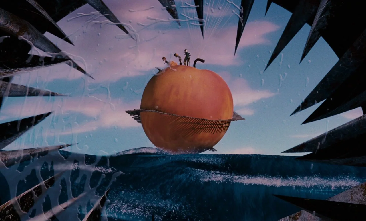 James and the Giant Peach (1996) movie still: wide — A gargantuan peach sits upon dark blue ocean waves beneath a light purple sky. The frame is…