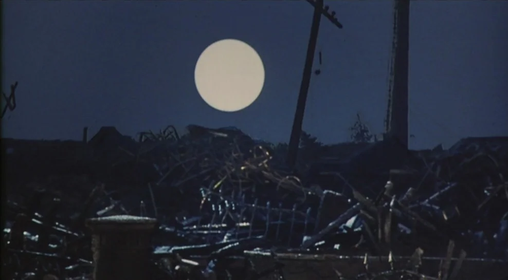 Madadayo (1993) movie still: establishing — A dark junkyard is filled with piles of twisted metal and discarded industrial waste. A large, perfectly…