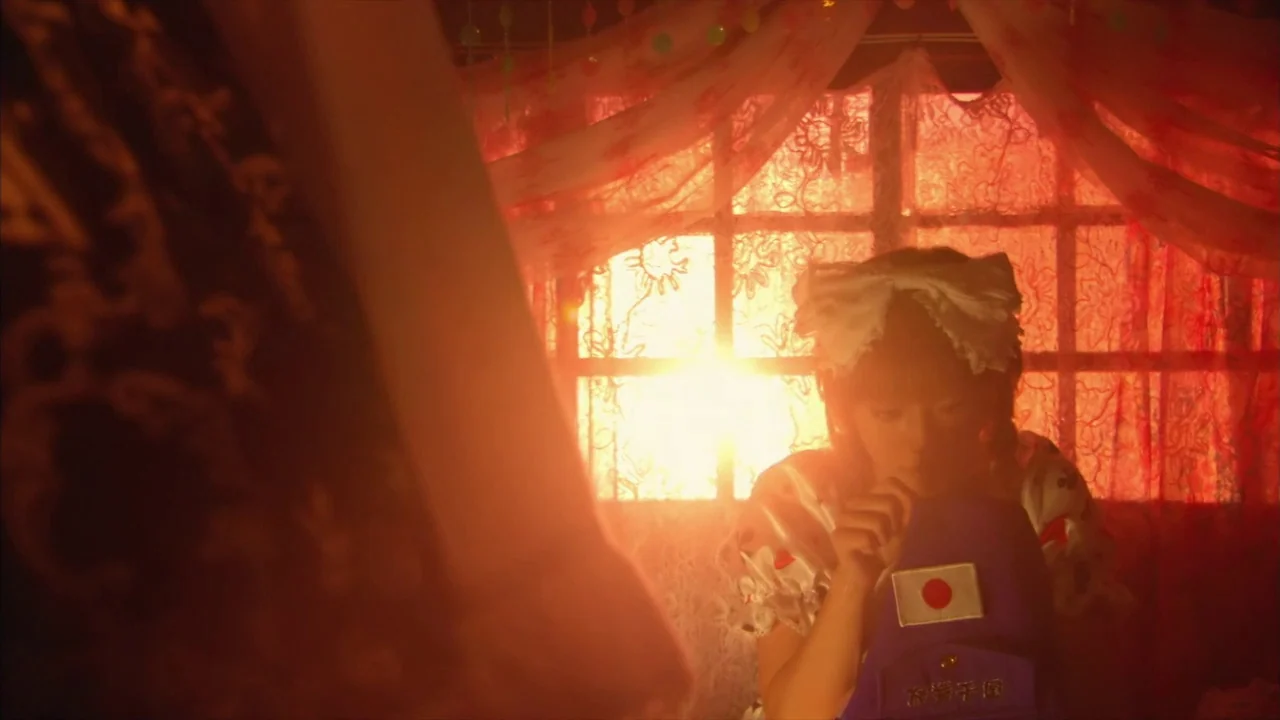 Kamikaze Girls (2004) movie still: medium — A window decorated with red lace curtains allows intense sunlight to fill a room. A young woman with a…