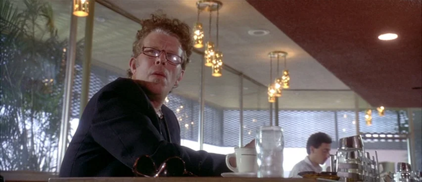 Short Cuts (1993) movie still: medium — A mid-century style diner interior features glass walls and modern decorative hanging light fixtures. A man…