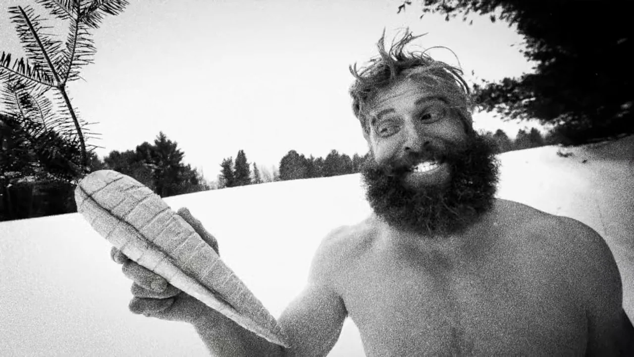 Hundreds of Beavers (2022) movie still: medium — A snowy outdoor landscape with evergreen branches in the background and a bright sky. A shirtless…