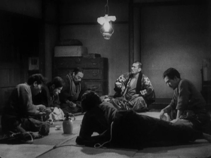 Sanshiro Sugata (1943) movie still: wide — A dim room features a low ceiling with a single hanging lantern casting light. Five men sit on woven mats…