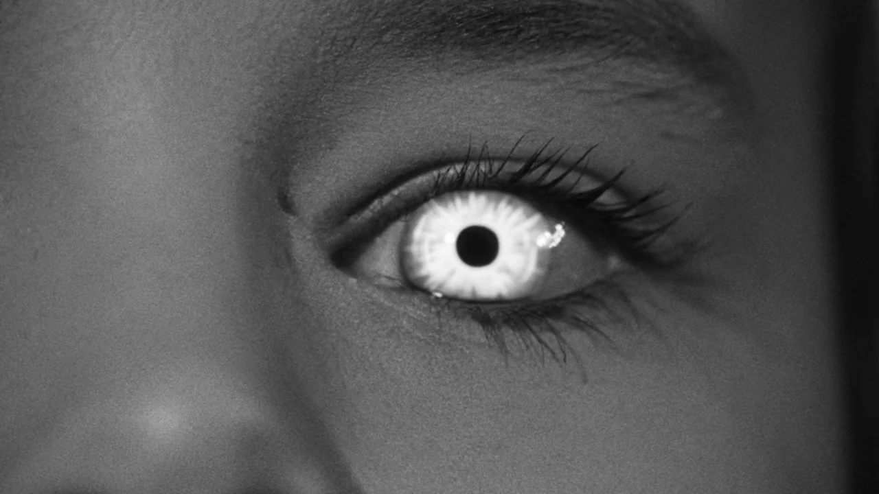 Village of the Damned (1960) movie still: closeup — An extreme close up of a single human eye in black and white. The eye remains motionless while…