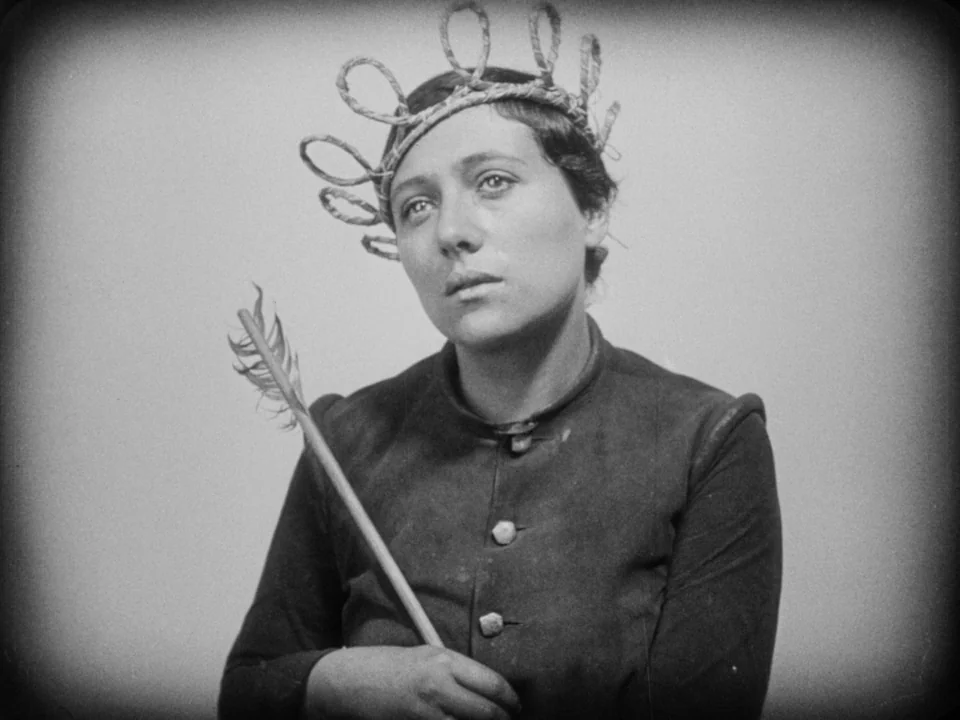 The Passion of Joan of Arc (1928) movie still: medium — A plain studio background serves as the backdrop for a portrait. A young woman wears a straw…