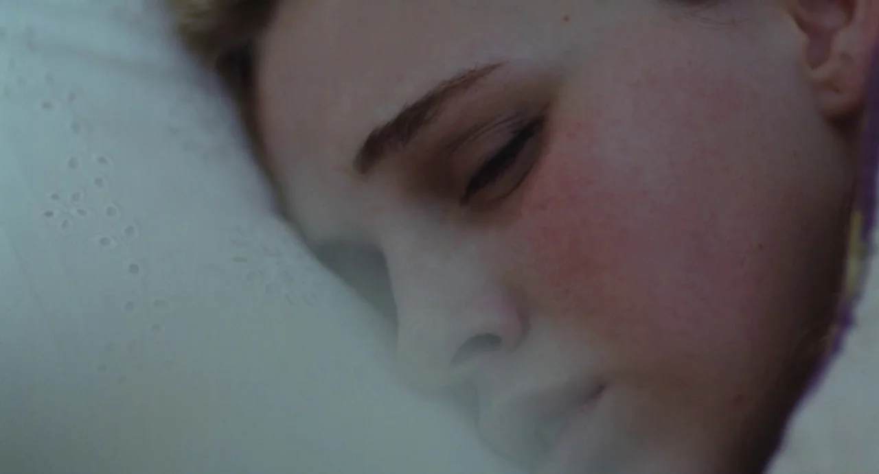 The Giant (2019) movie still: closeup — A close-up view shows a person sleeping on a white textured pillow. The subject lies in profile with eyes…