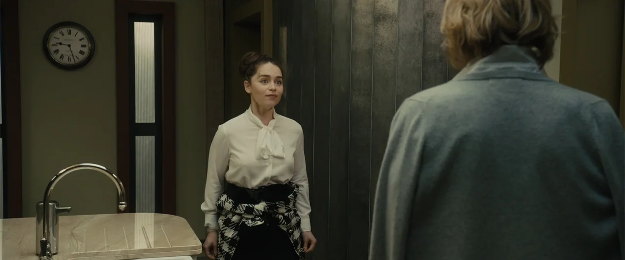 Me Before You (2016) movie still: medium — A modern, minimalist kitchen features dark metallic cabinetry and a marble-topped island surface. A young…