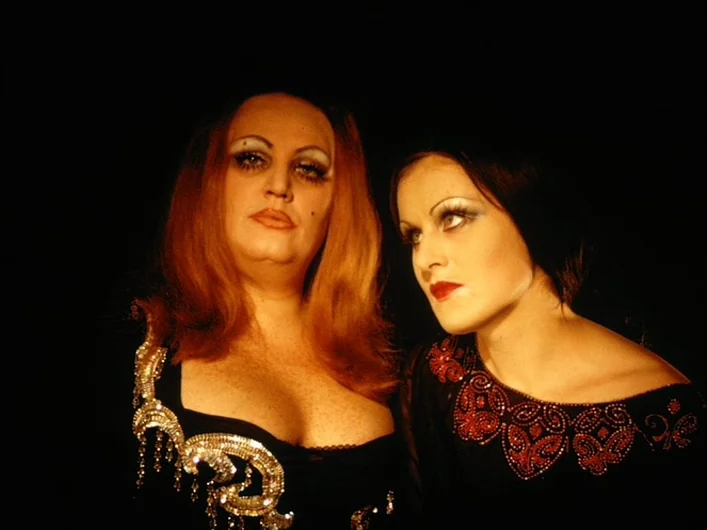 The Death of Maria Malibran (1972) movie still: medium — Two women stand in front of a completely black background. The subjects wear ornate black…