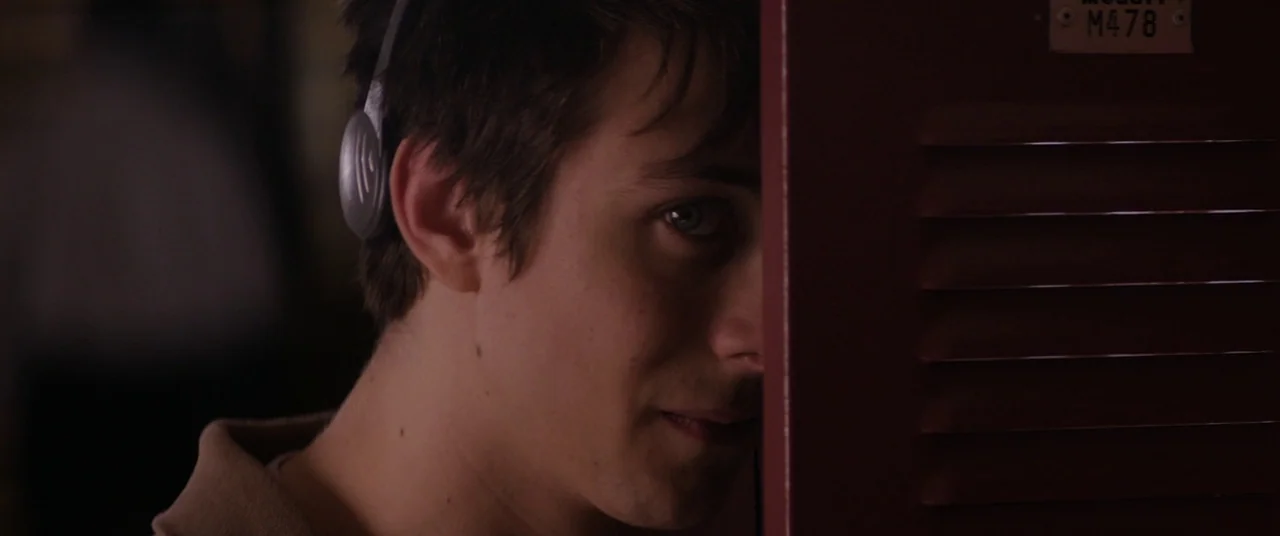 Super Dark Times (2017) movie still: closeup — A dimly lit school hallway features a red metal locker with a numbered tag. A teenage boy with…