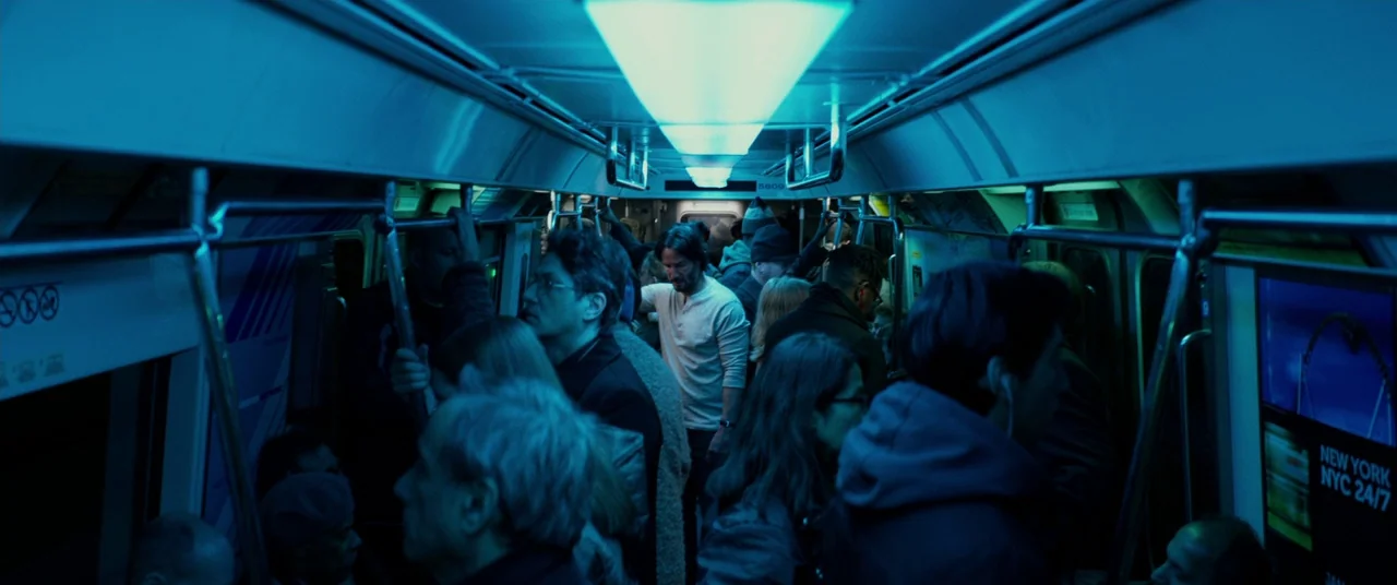 John Wick: Chapter 2 (2017) movie still: wide — A crowded public transport subway car features rows of standing passengers under cool lighting. The…