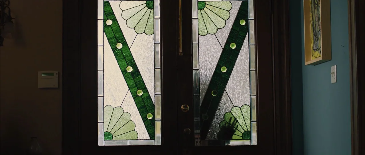 The Truth About Emanuel (2013) movie still: medium — An interior entryway features a dark wooden door with elaborate green and clear stained glass.…
