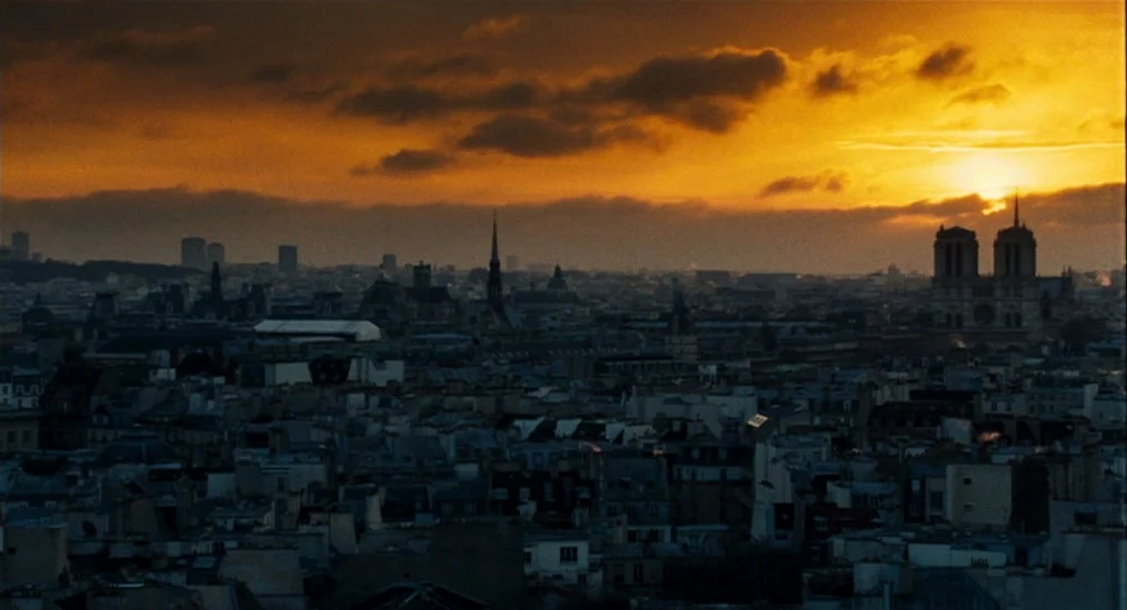 Paris, Je T’Aime (2006) movie still: establishing — A panoramic view of Paris features dense urban architecture under a vibrant orange sunset.…