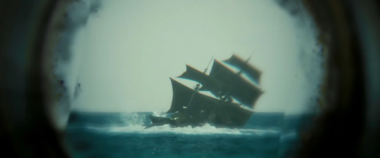 Pirates of the Caribbean: Dead Man’s Chest movie still: wide — A historic wooden sailing ship moves through rough, choppy ocean waters. The view is…