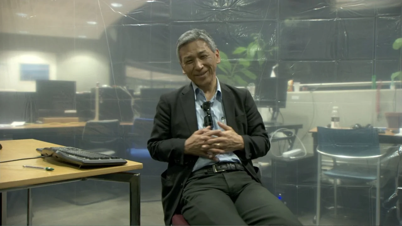 CERN (2013) movie still: medium — An office environment is partitioned by a clear plastic safety screen.
