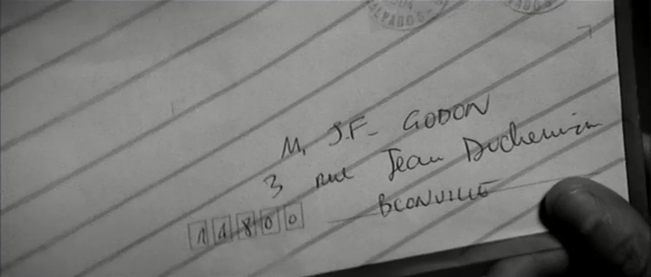 13 Tzameti (2006) movie still: closeup — A close-up view shows a hand holding a piece of lined stationery. Handwritten text and postal boxes are…
