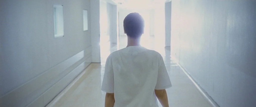 Code 46 movie still: medium — A stark white, long hospital corridor with smooth walls and polished floors.
